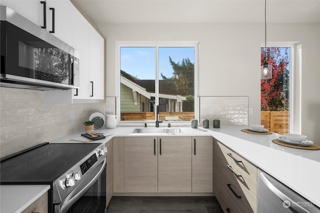 kitchen featuring sink, tasteful backsplash, dark hardwood / wood-style flooring, pendant lighting, and appliances with stainless steel finishes