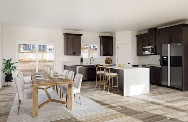 kitchen with a kitchen island, appliances with stainless steel finishes, a breakfast bar, sink, and dark brown cabinetry