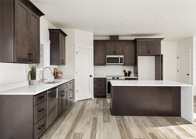 kitchen with sink, a center island, dark brown cabinetry, stainless steel appliances, and light wood-type flooring