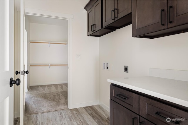 washroom featuring hookup for a washing machine, electric dryer hookup, light wood-type flooring, and cabinets