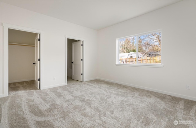 unfurnished bedroom with a spacious closet and light colored carpet