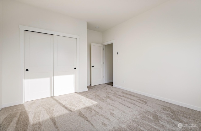 unfurnished bedroom with light colored carpet and a closet