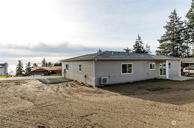 rear view of property featuring a garage and ac unit