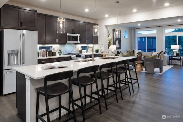 kitchen featuring pendant lighting, premium appliances, and an island with sink