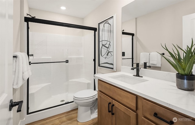 bathroom with hardwood / wood-style floors, vanity, toilet, and an enclosed shower