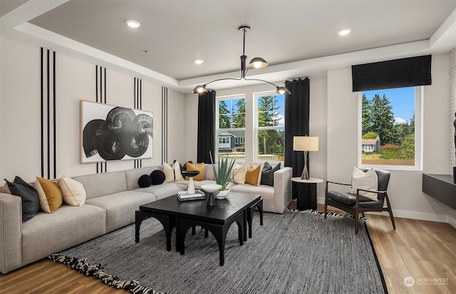 living room with a tray ceiling and light hardwood / wood-style flooring