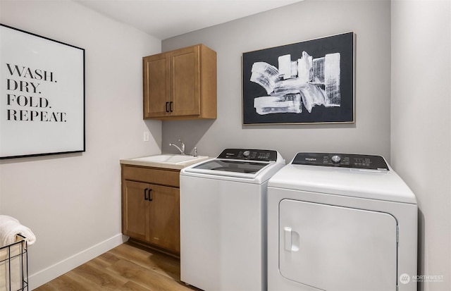 clothes washing area featuring light hardwood / wood-style floors, cabinets, separate washer and dryer, and sink