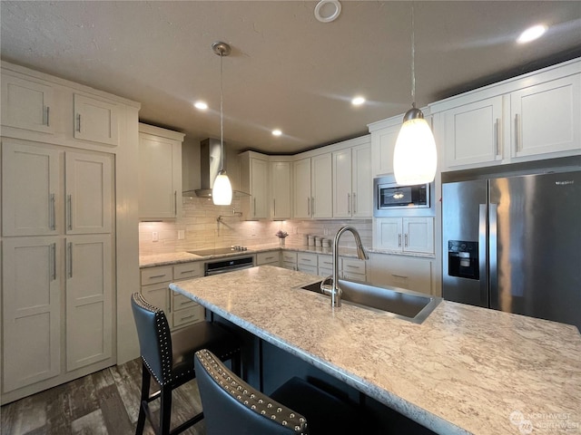 kitchen featuring a kitchen breakfast bar, sink, wall chimney exhaust hood, dark hardwood / wood-style floors, and decorative light fixtures