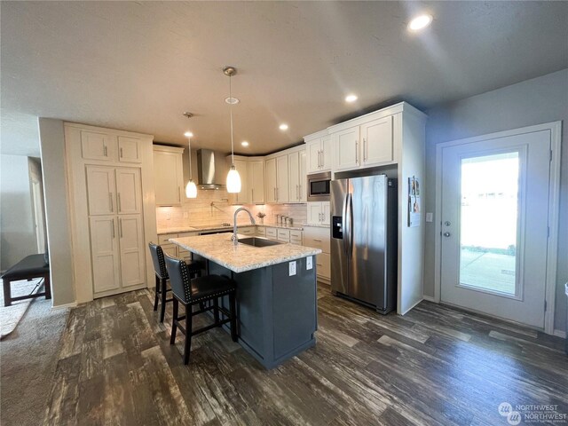 kitchen featuring appliances with stainless steel finishes, a kitchen island with sink, sink, pendant lighting, and white cabinetry