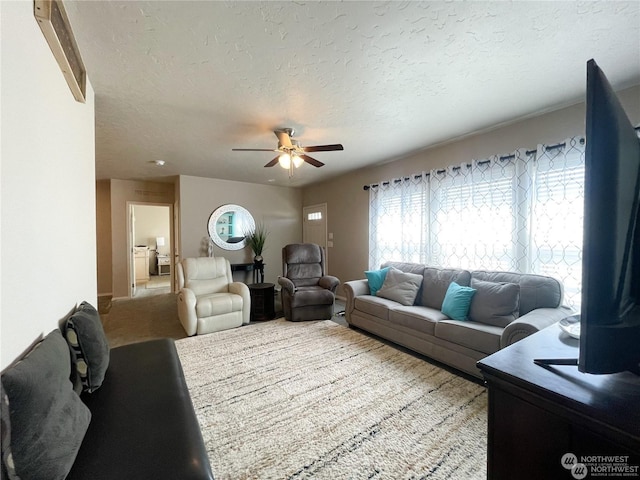 carpeted living room with ceiling fan and a textured ceiling