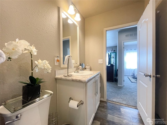 bathroom with hardwood / wood-style floors, vanity, and toilet