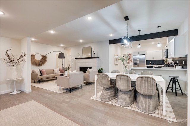 dining room with a tile fireplace and light hardwood / wood-style floors