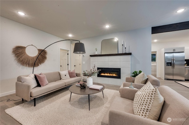 living room featuring light wood-type flooring and a tile fireplace