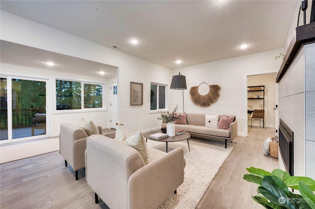 living room featuring light hardwood / wood-style floors and a tiled fireplace