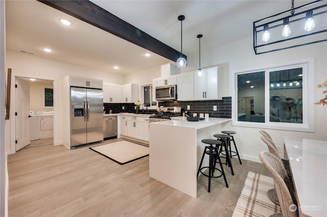 kitchen featuring kitchen peninsula, stainless steel appliances, beamed ceiling, white cabinetry, and hanging light fixtures