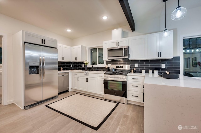 kitchen with decorative backsplash, white cabinetry, hanging light fixtures, and stainless steel appliances