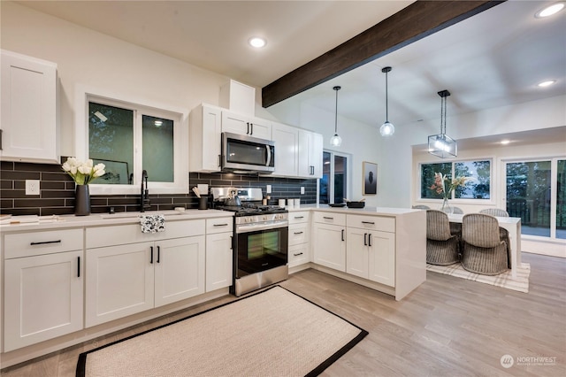 kitchen with appliances with stainless steel finishes, white cabinetry, and hanging light fixtures