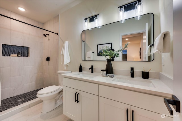 bathroom featuring vanity, toilet, and a tile shower