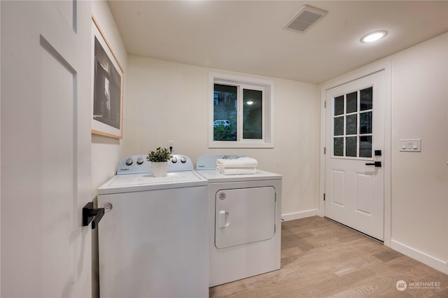 clothes washing area with washing machine and dryer and light hardwood / wood-style floors