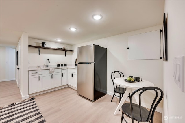 kitchen featuring white cabinets, light hardwood / wood-style floors, sink, and stainless steel refrigerator