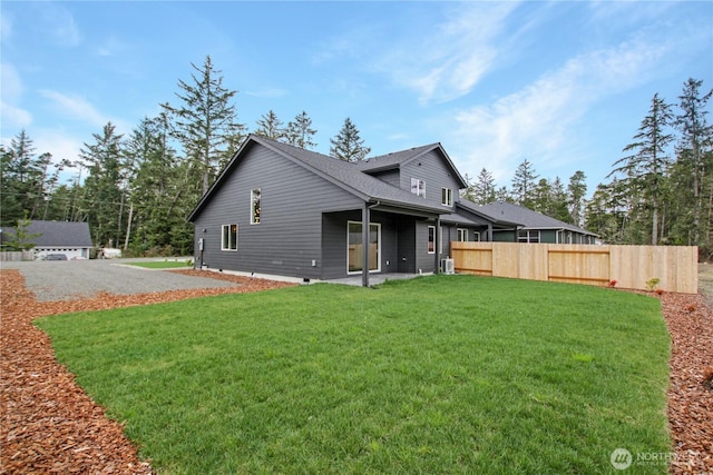 back of property featuring fence, a lawn, and crawl space