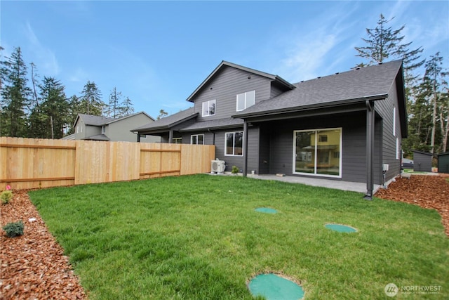 rear view of property with a yard, a patio, a shingled roof, and fence