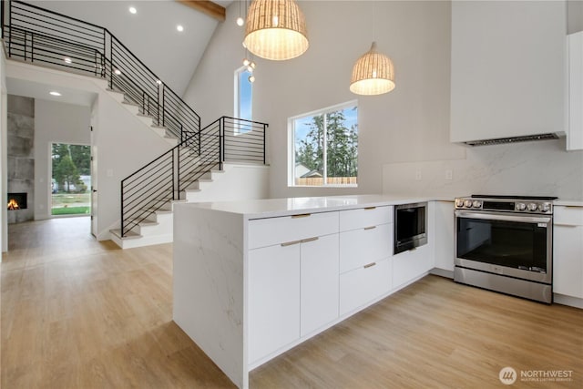 kitchen featuring built in microwave, stainless steel electric range oven, light wood-type flooring, and modern cabinets