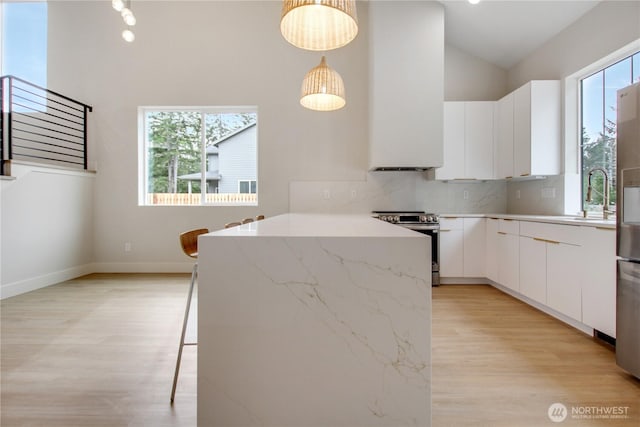 kitchen featuring pendant lighting, a sink, stainless steel electric stove, light wood-style floors, and white cabinets