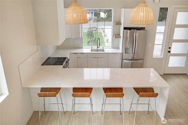 kitchen with stainless steel fridge with ice dispenser, light wood-type flooring, a peninsula, electric range, and a sink