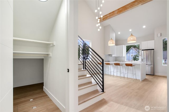 stairway featuring beamed ceiling, high vaulted ceiling, wood finished floors, recessed lighting, and baseboards