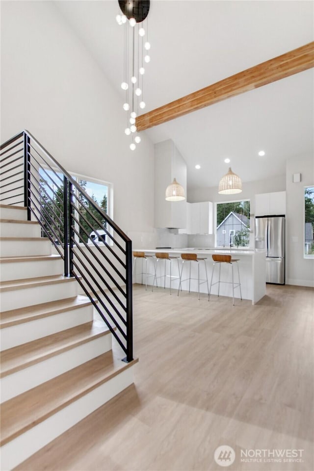 stairway with recessed lighting, wood finished floors, and high vaulted ceiling