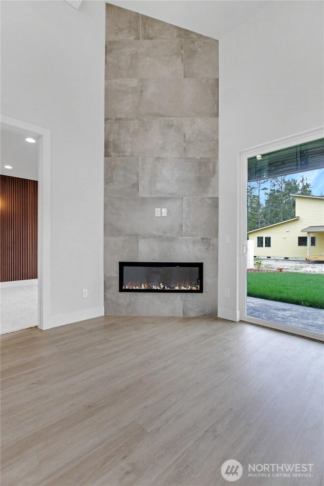 unfurnished living room featuring wood finished floors, a high ceiling, and a fireplace