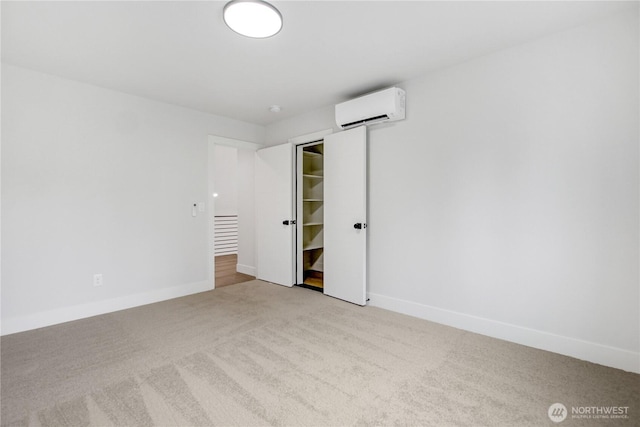 spare room with carpet flooring, a wall mounted AC, and baseboards