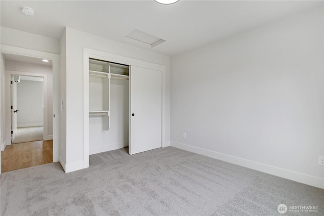 unfurnished bedroom featuring baseboards, attic access, and carpet