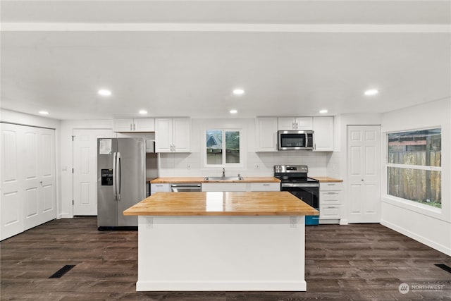 kitchen featuring dark wood-type flooring, white cabinets, stainless steel appliances, and wood counters