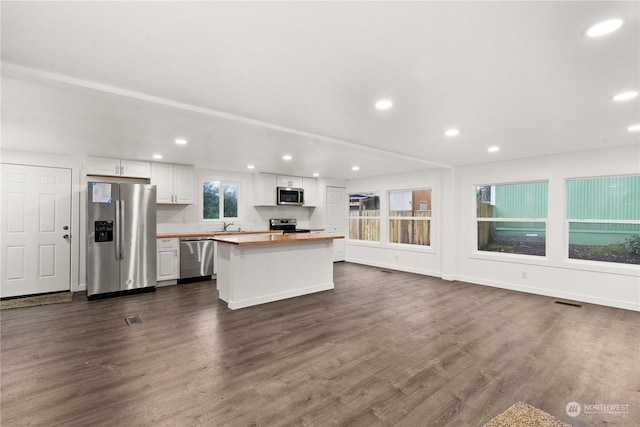 kitchen with wood counters, stainless steel appliances, a kitchen island, dark wood-type flooring, and white cabinetry