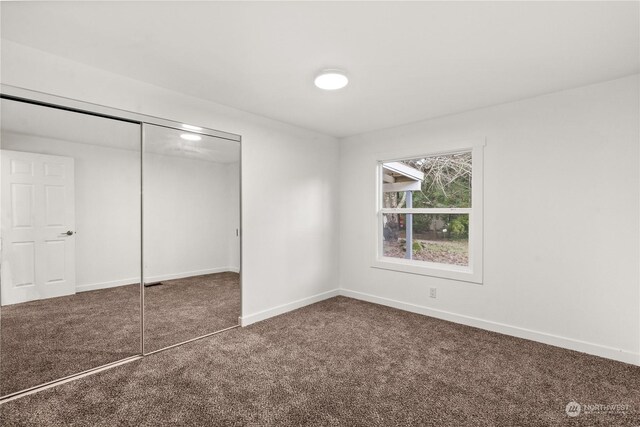 unfurnished bedroom with dark carpet and a closet