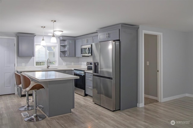 kitchen with sink, a kitchen island, light hardwood / wood-style floors, and appliances with stainless steel finishes