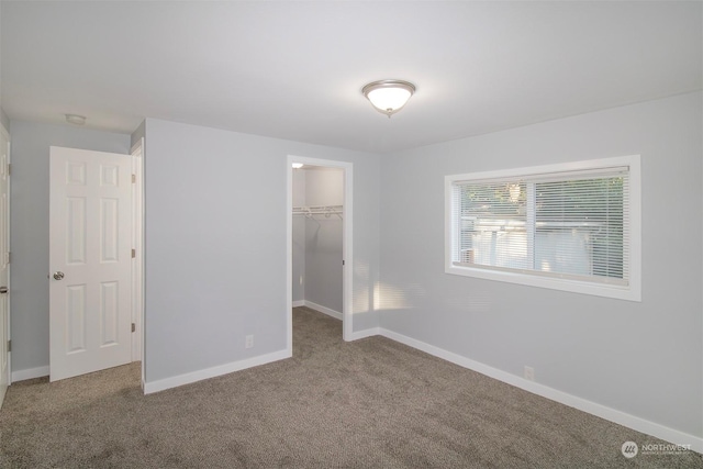 unfurnished bedroom with carpet, a walk in closet, and a closet