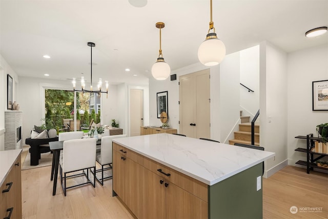 kitchen featuring light stone countertops, pendant lighting, a center island, and light hardwood / wood-style flooring