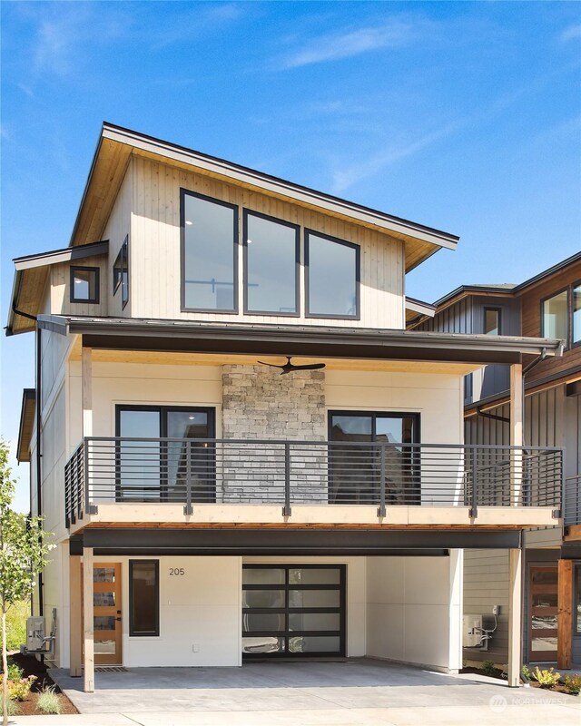 205 Riverwalk Dr, Lynden, WA 98264 - view of front facade featuring a balcony, a garage, driveway, and stone siding