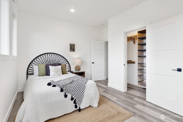 bedroom with a spacious closet and hardwood / wood-style flooring