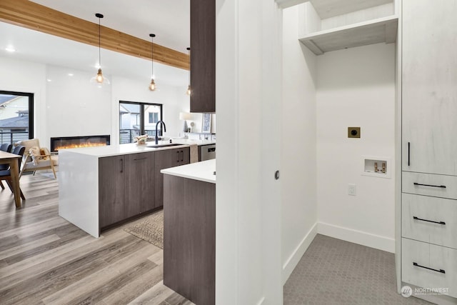 kitchen with dark brown cabinets, sink, pendant lighting, beam ceiling, and light hardwood / wood-style floors