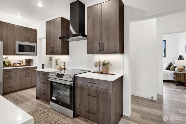 205 Riverwalk Dr, Lynden, WA 98264 - kitchen featuring stainless steel appliances, wall chimney range hood, light wood-type flooring, light countertops, and recessed lighting