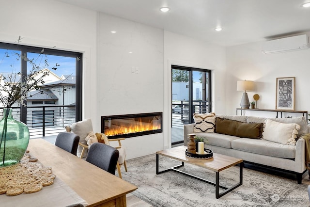 living room featuring a wall mounted AC, a large fireplace, and a healthy amount of sunlight