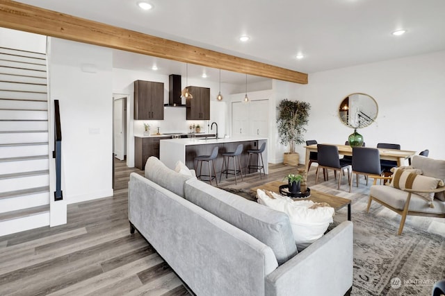 living room with beam ceiling, light hardwood / wood-style flooring, and sink