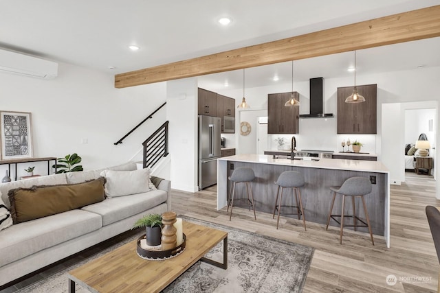 living room featuring beamed ceiling, light hardwood / wood-style floors, sink, and a wall unit AC