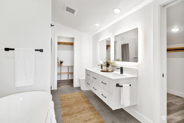 bathroom with a bathtub, vanity, vaulted ceiling, wood-type flooring, and toilet