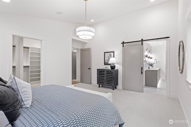 carpeted bedroom featuring ensuite bathroom, a barn door, a spacious closet, and a closet