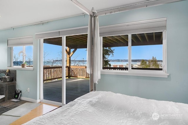 bedroom featuring access to exterior, a water view, and light hardwood / wood-style flooring